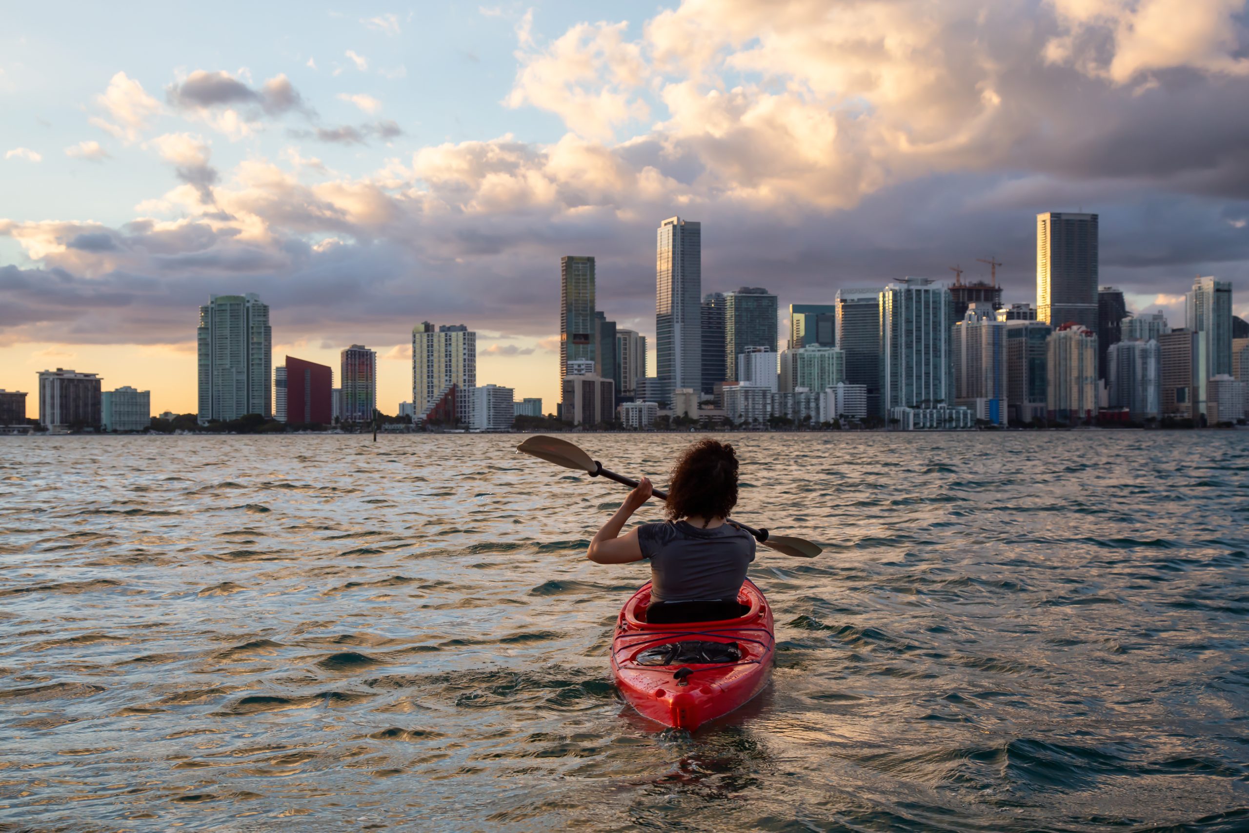 Kayaker on Biscayne Bay heading toward Miami skyline representing EEG tech career opportunities in Florida